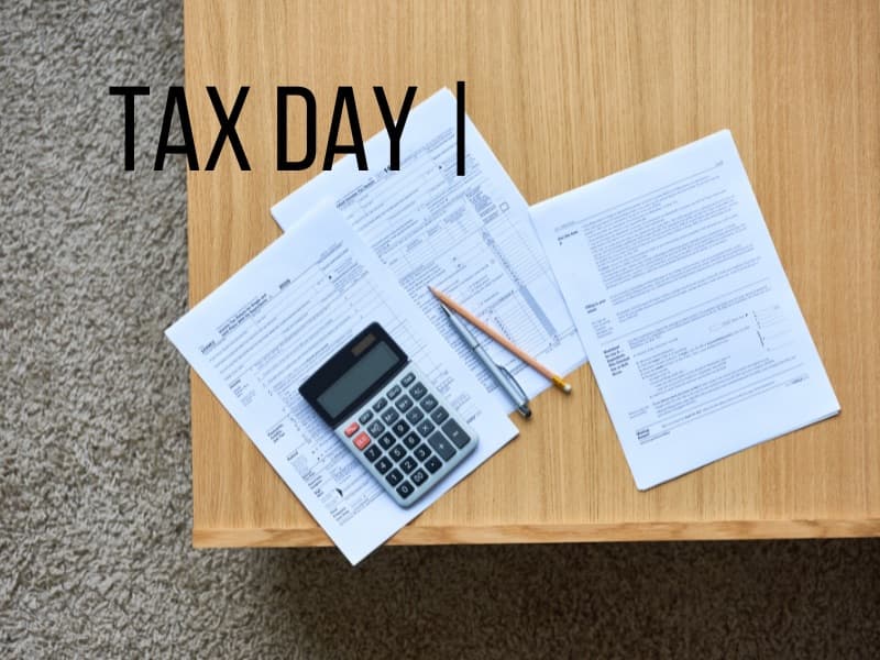 木桌上面嘅報稅文件、計算機同寫住「TAX DAY」嘅便條